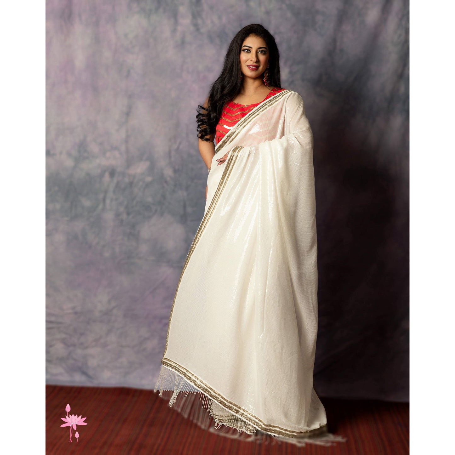 Woman wearing a white saree with a red blouse against a textured gray background