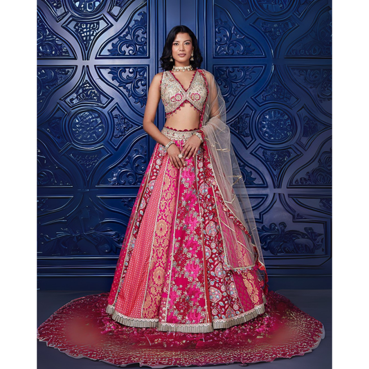 Woman in a traditional pink and red embroidered outfit against a blue decorative wall.